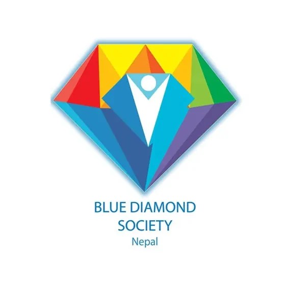 A colorful diamond-shaped logo with triangular sections in red, yellow, green, blue, and purple. At the center is a white figure with arms raised, set against a blue triangle. Below, the text reads "BLUE DIAMOND SOCIETY Nepal."