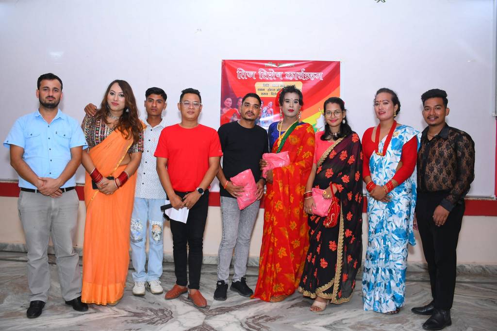 nine people standing in a row against a wall with a banner on it