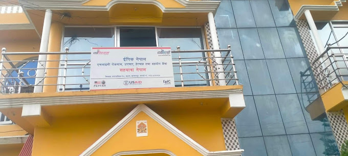 front of orange building with lots of windows and a sign indicating the building and USAID